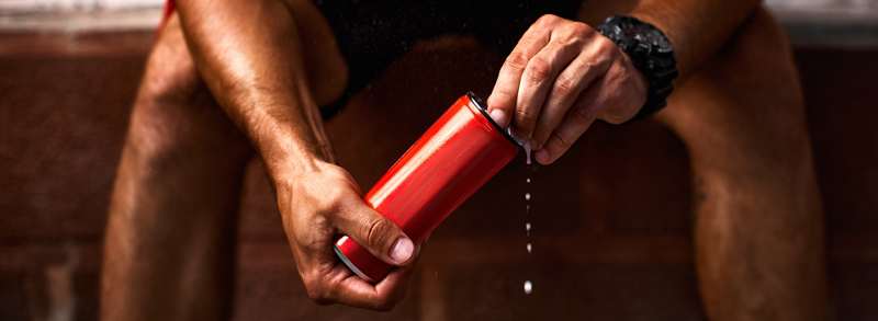 Close-up of a person holding a red clean energy drink can, representing the growing trend of wellness-focused beverage options.