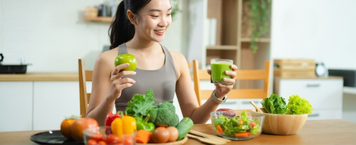 Woman drinking a healthy beverage at a kitchen table, representing innovation opportunities for flavor developers