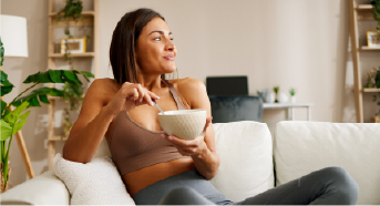 Woman relaxing on a sofa with a snack, eating for comfort and mood