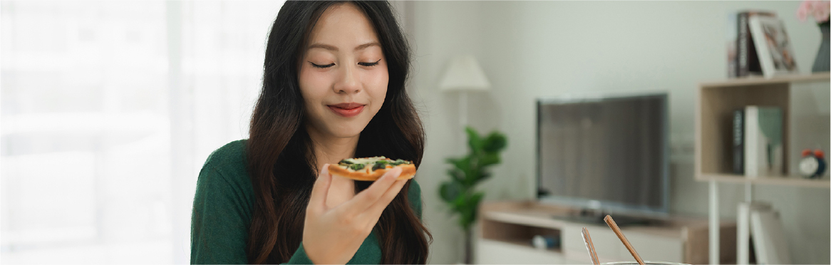 A woman smiling as she tastes her food, reflecting satisfaction with balanced, nuanced flavors.
