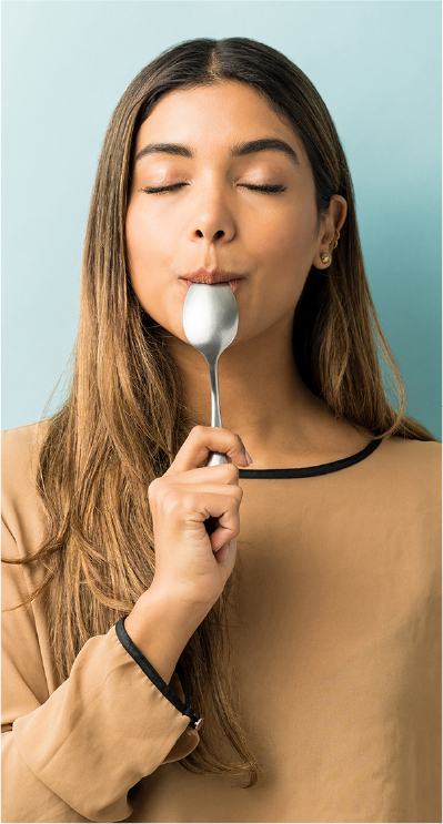 A woman tasting food with her eyes closed, illustrating sensory fatigue and palate overload.