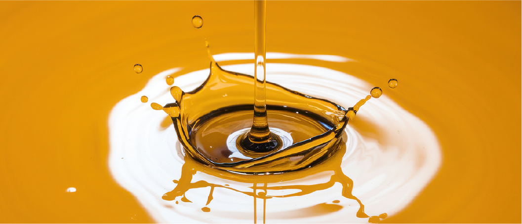 Golden liquid dripping into a bowl and creating ripples, illustrating the study of mouthfeel and flow behavior.