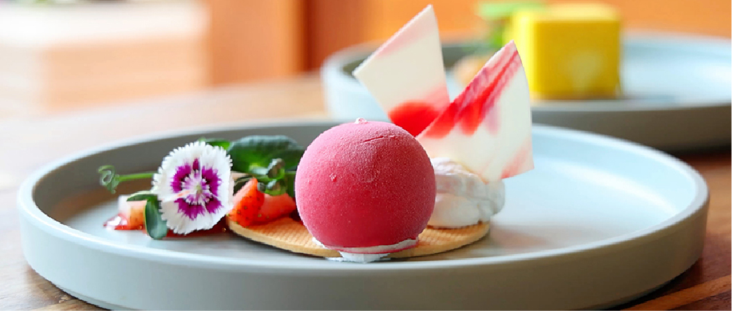 A plated red sorbet dessert with floral garnish, illustrating creativity in global-inspired flavor pairings.