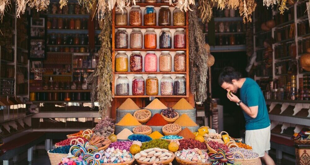 A man exploring vibrant spice jars in a traditional market filled with color and aroma.