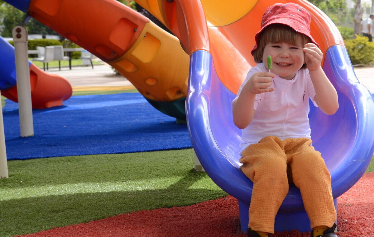 Child smiling on a playground slide, symbolizing how context and emotion shape flavor perception
