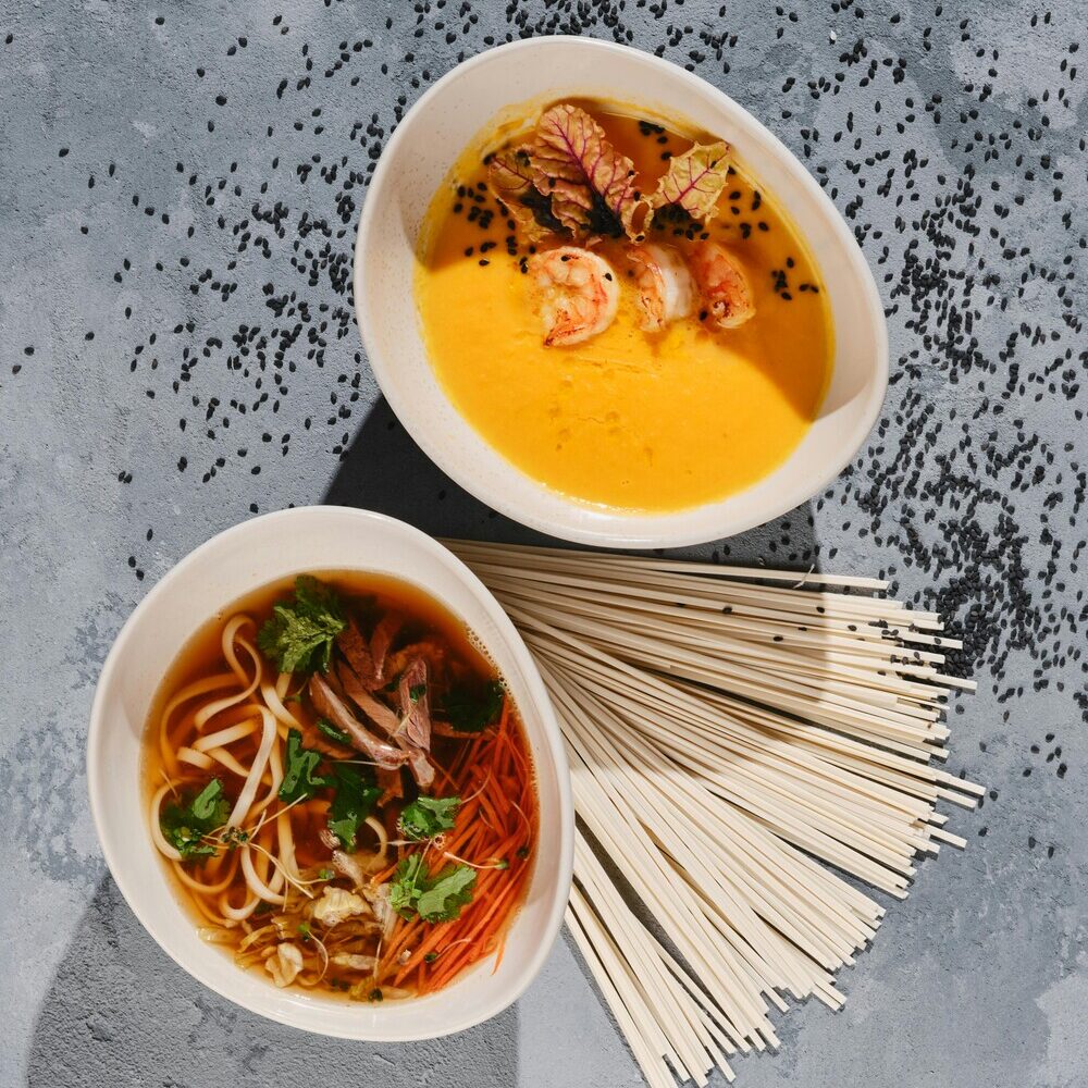 Two bowls of regional noodle soups with dried noodles, showing region-true cues in international flavor trends