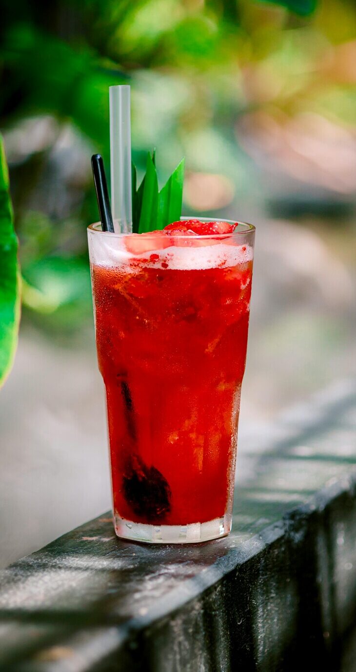 Red berry drink on a patio table, reinforcing ripe, sweet expectations from warm, congruent color cues.
