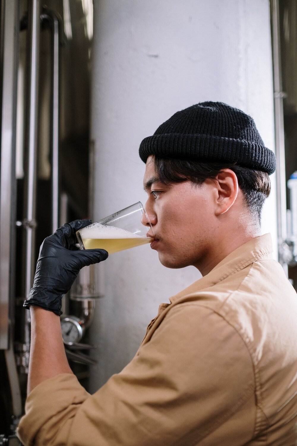 Person tasting a pale drink, representing repeated-sip testing for bitter finish and aftertaste.